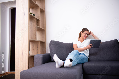 Beautiful woman using her tablet on a sofa in a living room