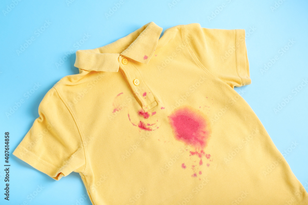 dirty stain from the juice on a children's T-shirt. isolated on blue background. dirty stain from the juice on a children's T-shirt. isolated on blue background.