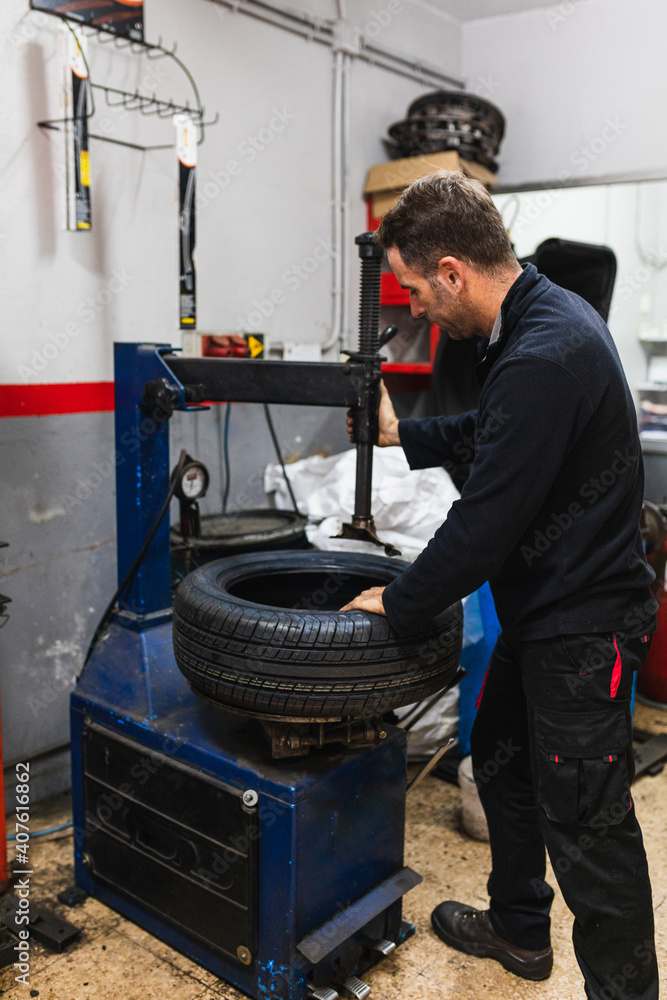Mechanic changing the rubber of a wheel. Automobile mechanics concept Mechanic changing the rubber of a wheel. Automobile mechanics concept
