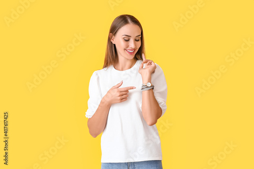 Beautiful woman with wristwatch on color background