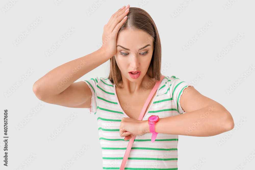 Stressed woman looking at wristwatch on light background Stressed woman looking at wristwatch on light background
