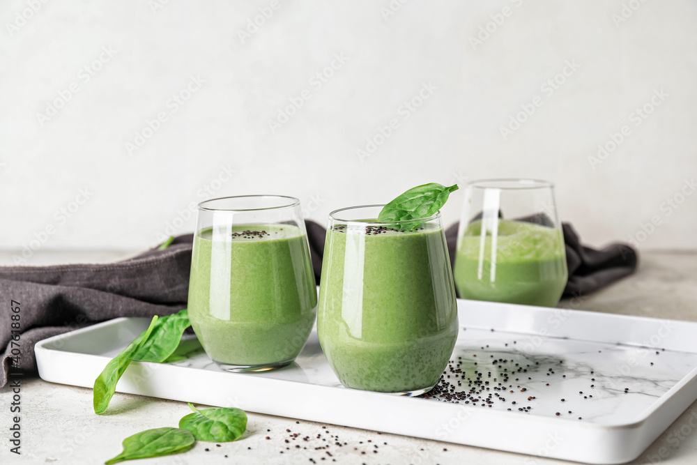 Glasses of healthy spinach smoothie on light table Glasses of healthy spinach smoothie on light table