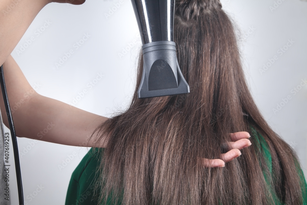 Fototapeta premium Girl drying hair with hairdryer in home.