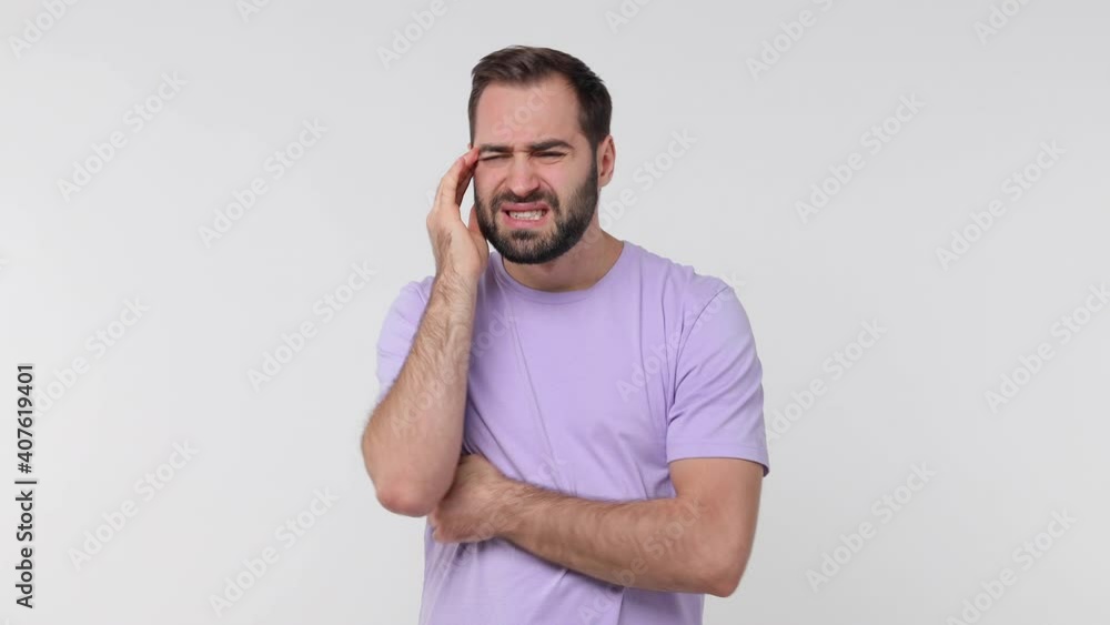 Sick ill bearded young man 20s years old in violet casual t-shirt isolated on white background studio. People lifestyle concept. Put hands on head rub temples having headache migraine feel bad seedy Sick ill bearded young man 20s years old in violet casual t-shirt isolated on white background studio. People lifestyle concept. Put hands on head rub temples having headache migraine feel bad seedy