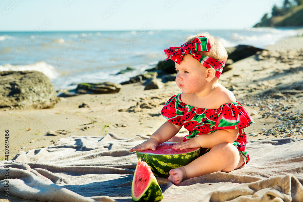 Little baby sits on a litter by the sea
near a piece of watermelon Little baby sits on a litter by the sea
near a piece of watermelon