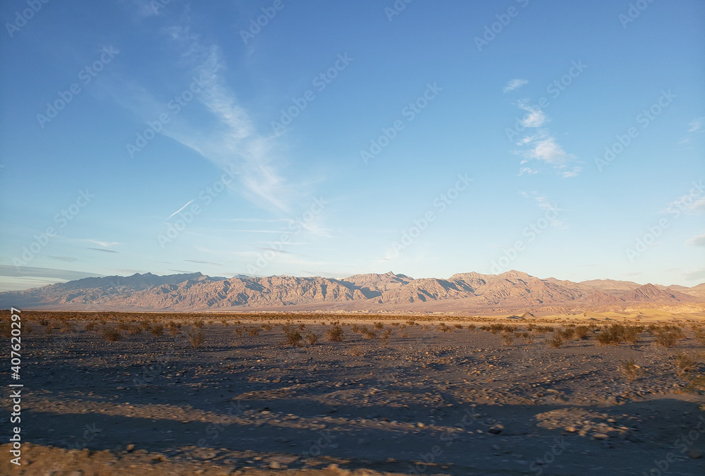 Beautiful shot of partly deserted land with rocky mountains on the horizon