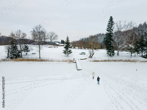 Aluksne, Latvia - 01.12.2021 Aerial view of People walking on frozen lake in Latvia.