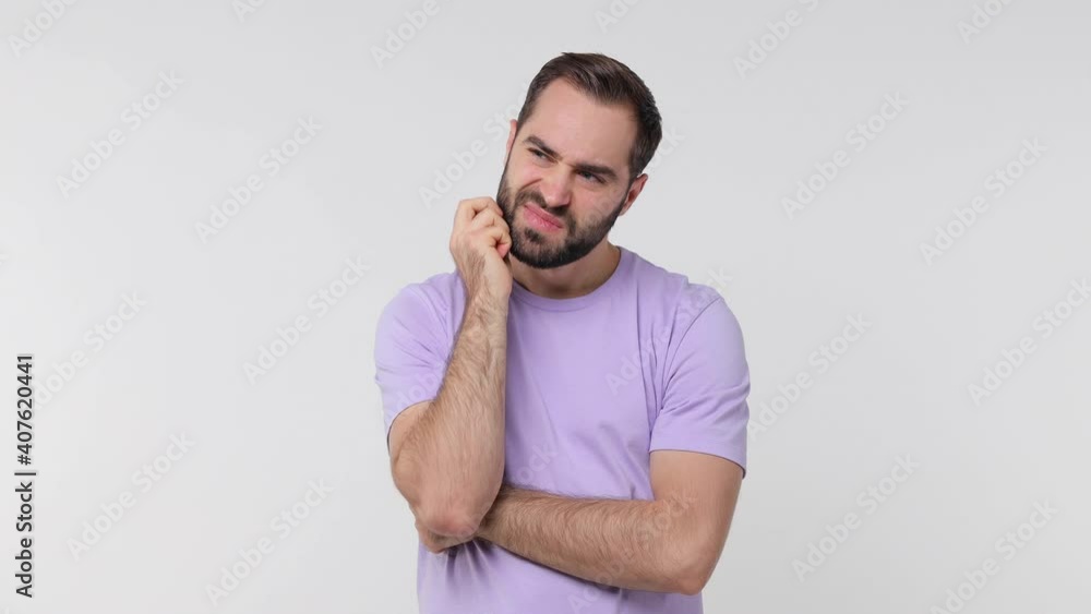 Preoccupied pensive bearded young man 20s years old in pastel violet casual t-shirt isolated on white color wall background studio. People lifestyle concept. Looking aside put hand prop up on chin Preoccupied pensive bearded young man 20s years old in pastel violet casual t-shirt isolated on white color wall background studio. People lifestyle concept. Looking aside put hand prop up on chin