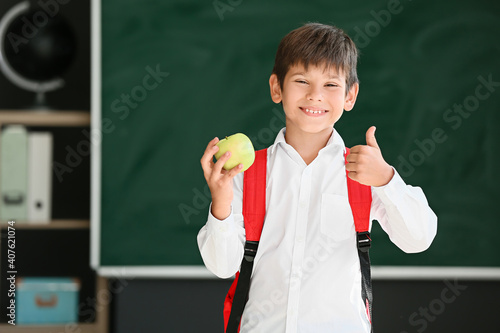 Schoolboy with apple against blurred background in school