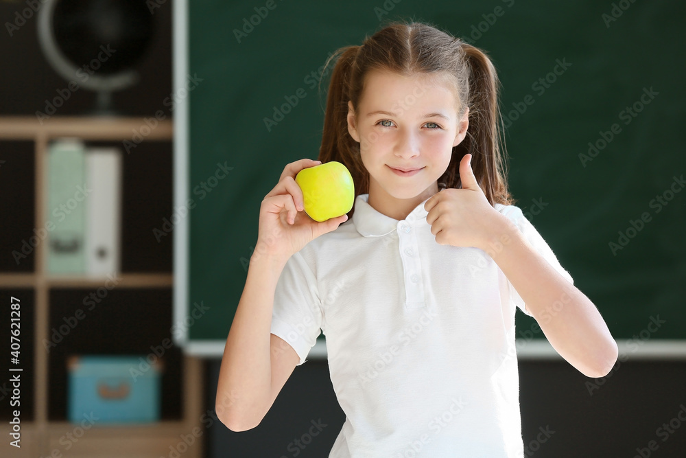 Schoolgirl with apple against blurred background in school Schoolgirl with apple against blurred background in school