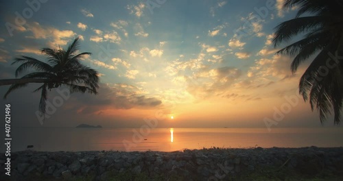 Colorful tropical sunset time lapse with palm trees sea view and island on horizon