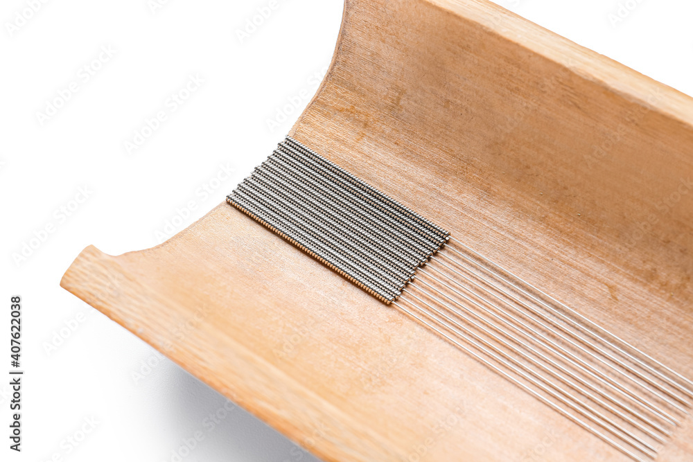 Bamboo tray with acupuncture needles on white background