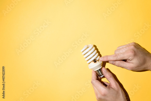 Male hands holding a burnt out light bulb. Hand showing the place of burnout. Top view, copy space