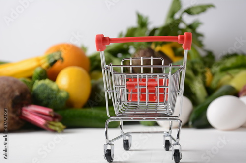 Shopping trolley cart and different groceries .Healthy food background. Healthy balanced food vegetables, fruit, bread, eggs. Shopping food supermarket, planning eating concept. photo