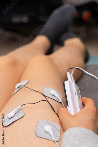 Someone using an electrostimulator on one leg. photo