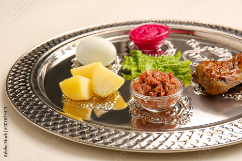Passover Seder plate with traditional food on light background, closeup