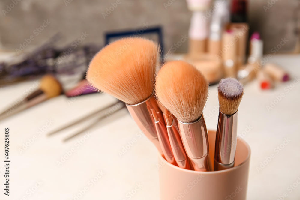Cup with makeup brushes on table, closeup - obrazy, fototapety, plakaty 