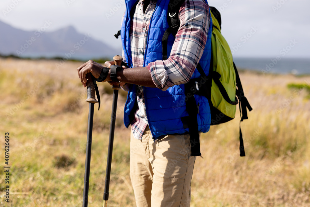 Fit african american man wearing backpack nordic walking on coast