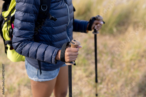 Fit african american woman wearing backpack nordic walking on coast