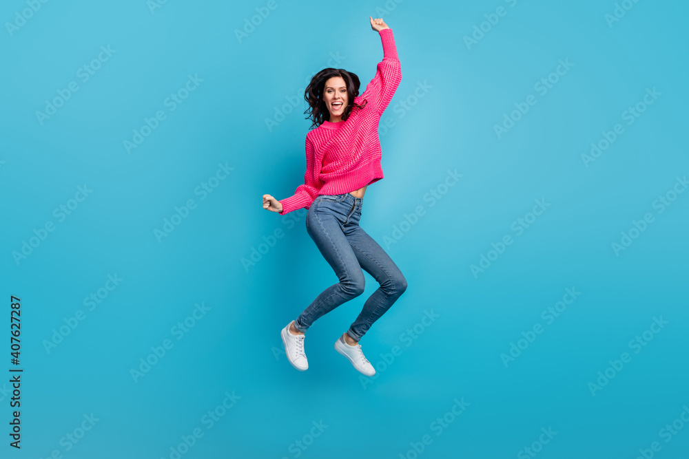 Full length portrait of astonished girl jump fists up open mouth shout yes isolated on blue color background