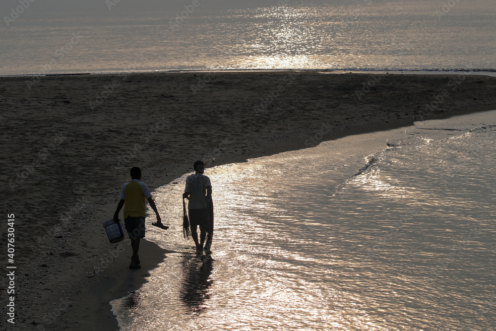 Two men walking by the sea for fish