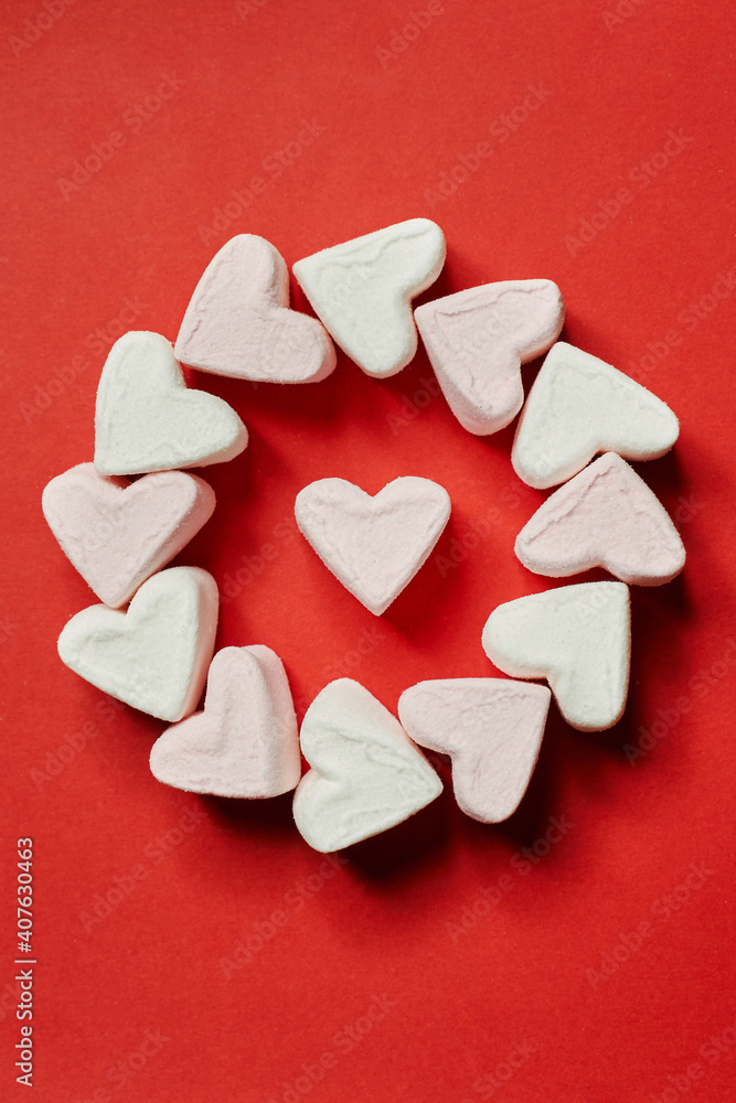Obraz premium on a red background, a circle of white marshmallows and one heart in the center