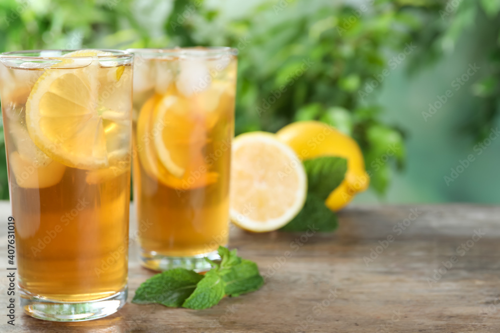 Delicious iced tea on wooden table outdoors, space for text