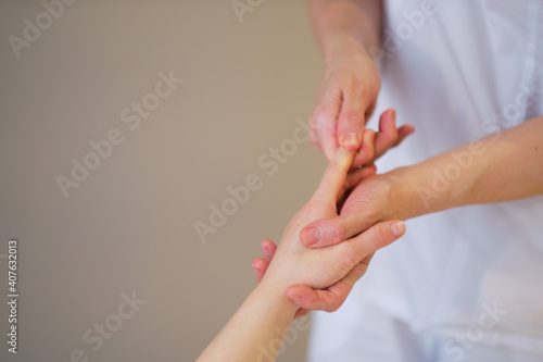 Wrist massage. massage therapist puts pressure on a sensitive point on a woman s hand. Physiotherapist massaging her patients hand in medical office