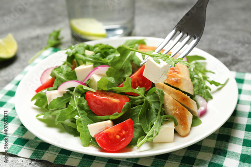 Delicious salad with meat, arugula and vegetables on grey table, closeup