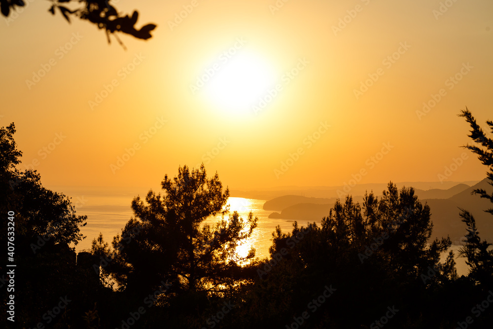 The sun sets on the horizon at sunset over the sea or ocean. Calm ocean sea waves. Natural sky in warm colors. Panoramic view,