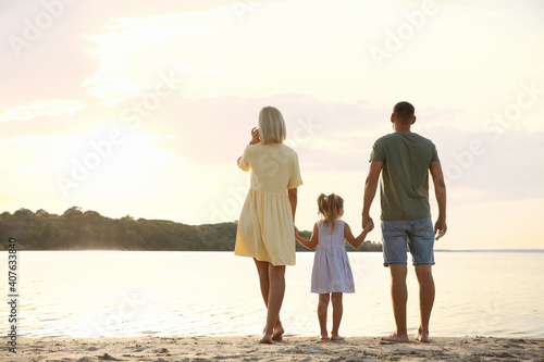 Happy parents with their child on beach  back view. Spending time in nature