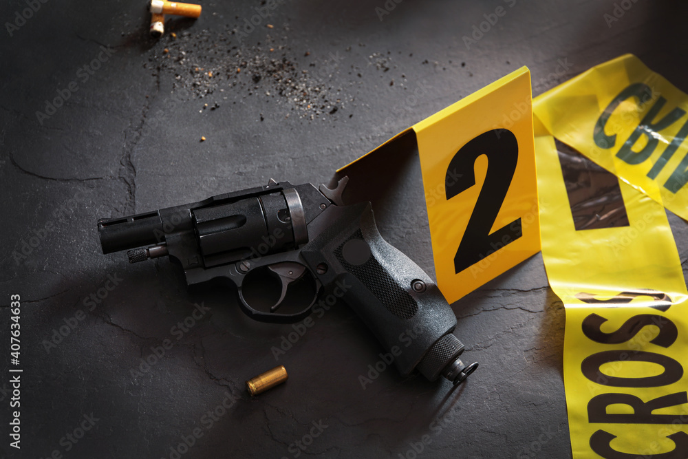 Composition with gun and shell casing on black slate table. Crime scene ...