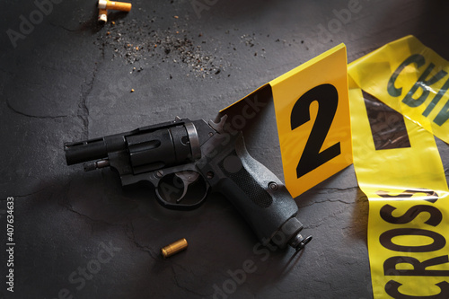 Composition with gun and shell casing on black slate table. Crime scene