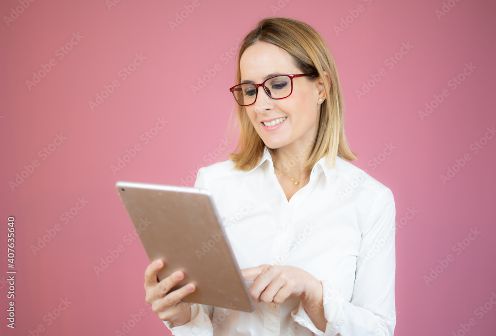 Smiling young woman holding digital tablet over pink background Smiling young woman holding digital tablet over pink background