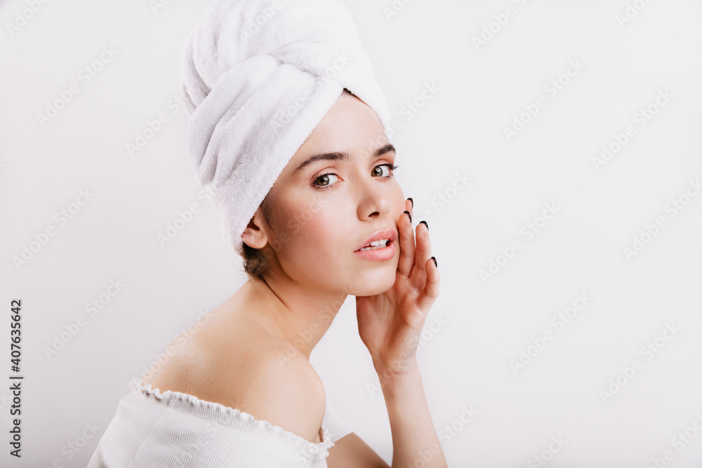Closeup portrait of model in towel on head. Girl without make-up gently touches her face Closeup portrait of model in towel on head. Girl without make-up gently touches her face