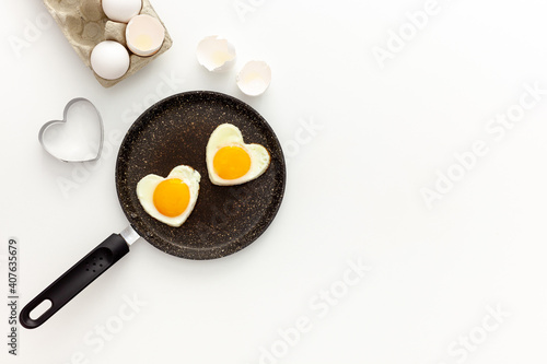 Cooking heart-shaped fried eggs in a pan