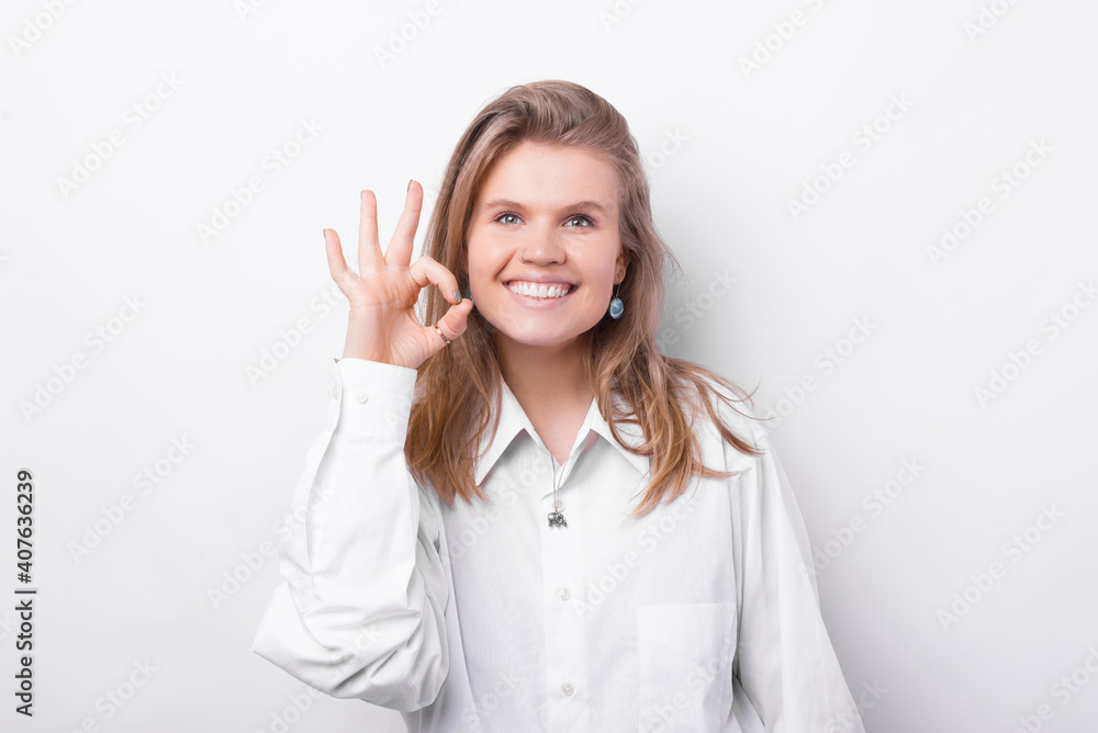 Photo of happy smiling young woman showing OK gesture over white background. Photo of happy smiling young woman showing OK gesture over white background.