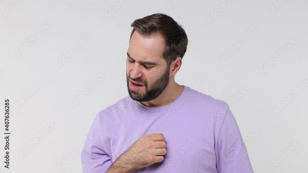 Sick ill bearded young man in violet t-shirt isolated on white background studio. People lifestyle concept. Coughing cover with hand put on sterile face mask to safe from coronavirus virus covid-19 Sick ill bearded young man in violet t-shirt isolated on white background studio. People lifestyle concept. Coughing cover with hand put on sterile face mask to safe from coronavirus virus covid-19