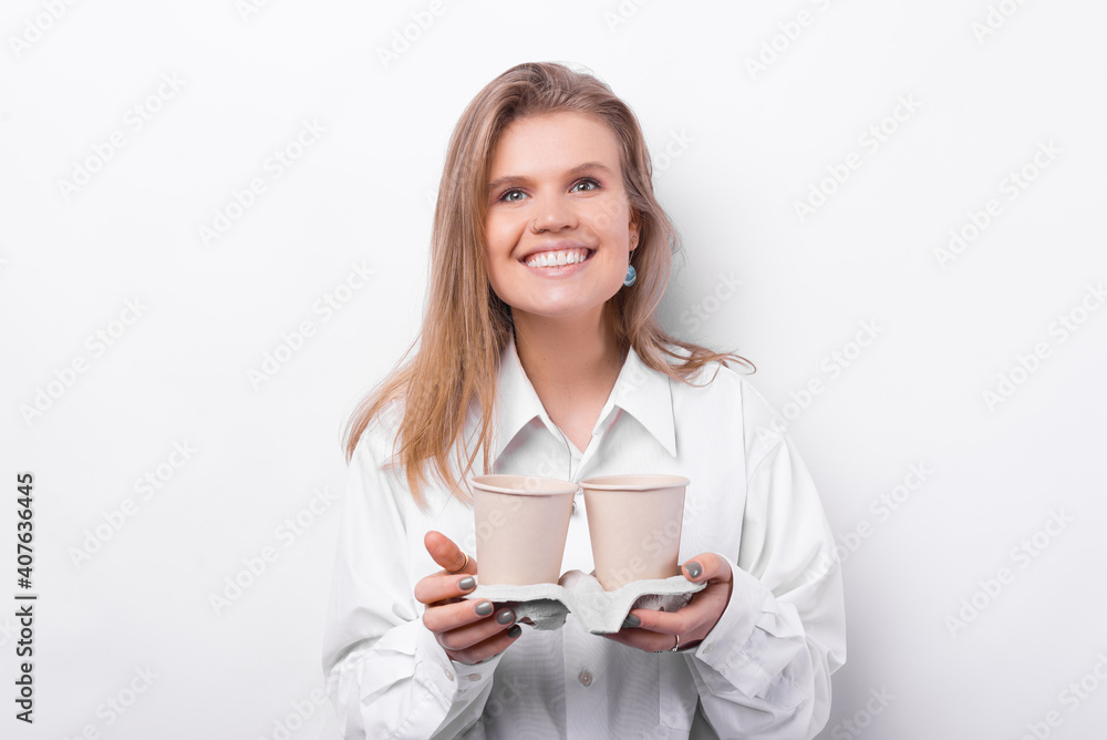 Cheerful young woman in white shirt holding two cups of coffee to take away. Cheerful young woman in white shirt holding two cups of coffee to take away.