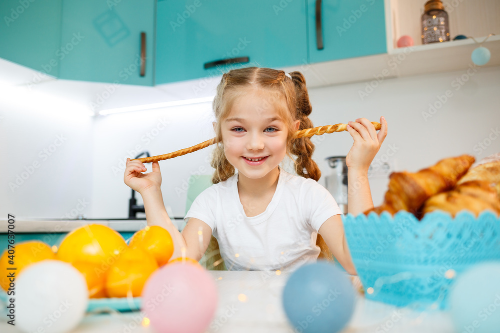 Portrait of a little girl 7 years old sits in the kitchen and plays with bread sticks. Child has breakfast in the kitchen Portrait of a little girl 7 years old sits in the kitchen and plays with bread sticks. Child has breakfast in the kitchen