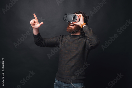 Amazed bearded man wearing VR and touching something in air.