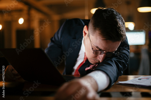 Tired businessman fell asleep in office. Exhausted man working on laptop