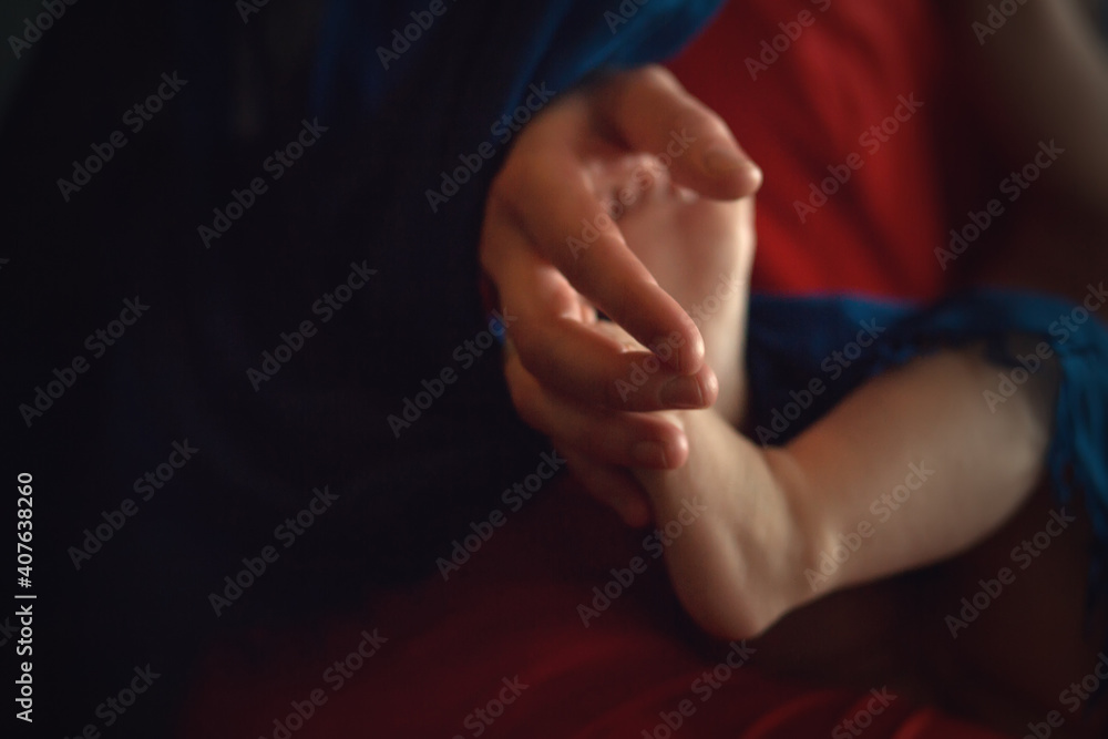 Mother's hand is holding her baby's toes. Image with selective focus and toning