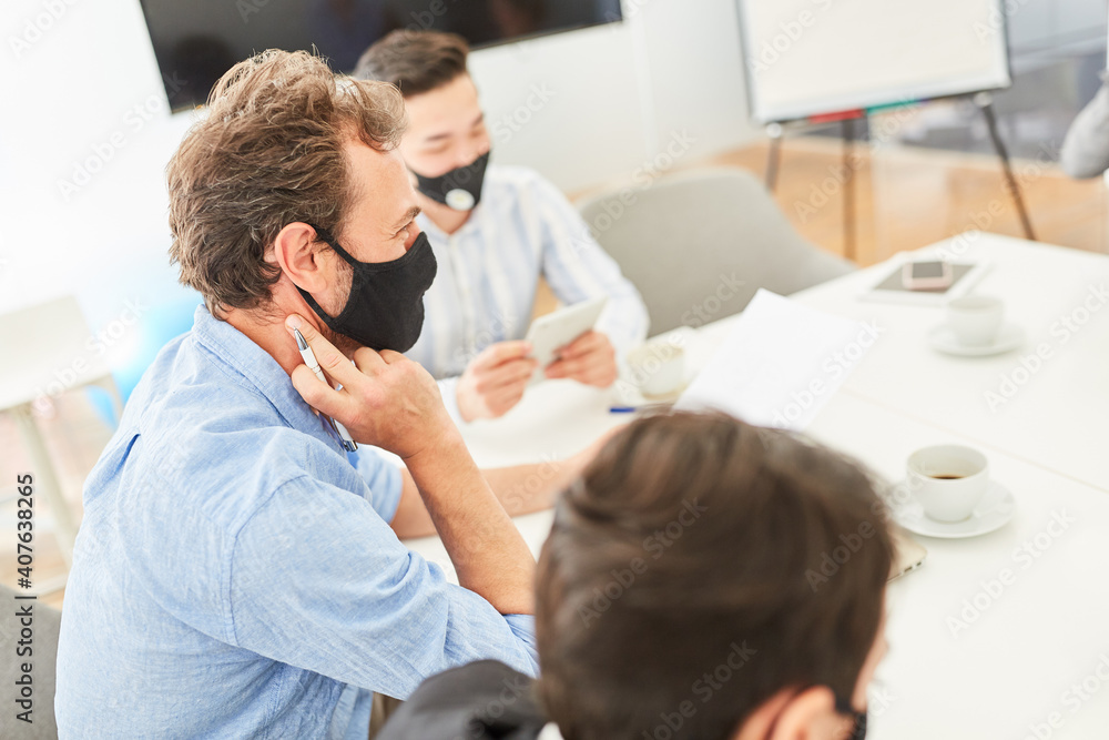 Obraz premium Business Team mit Mundschutz in einem Meeting