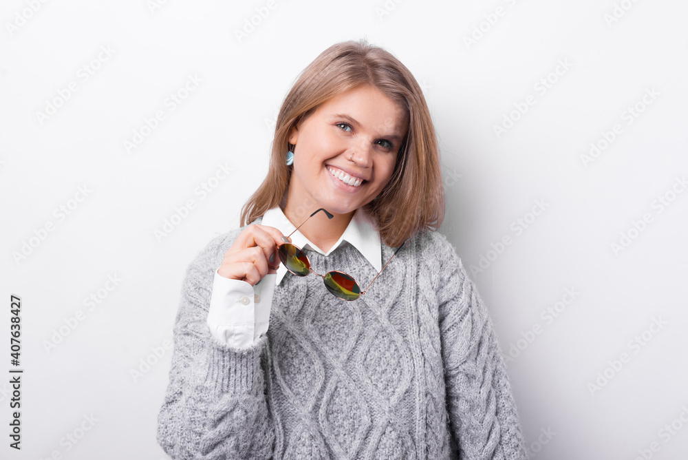 Portrait of joyful young woman in casual over white background holding sunglasses and looking at the camera. Portrait of joyful young woman in casual over white background holding sunglasses and looking at the camera.