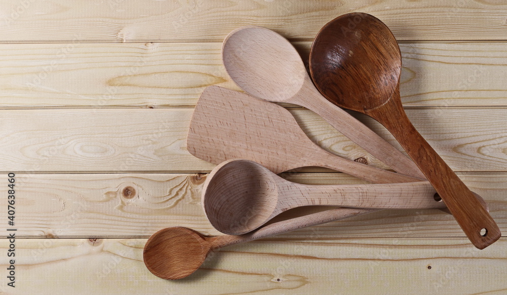 New spoons, ladles and spatula kitchen utensil set on wooden plank table, boards background and texture, top view New spoons, ladles and spatula kitchen utensil set on wooden plank table, boards background and texture, top view
