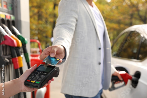 Man fills the car and paying with credit card at gas station, closeup