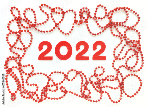 Red felt numbers 2022 on white background. Red beads around. Flat lay for Valentine's Day or New Year.