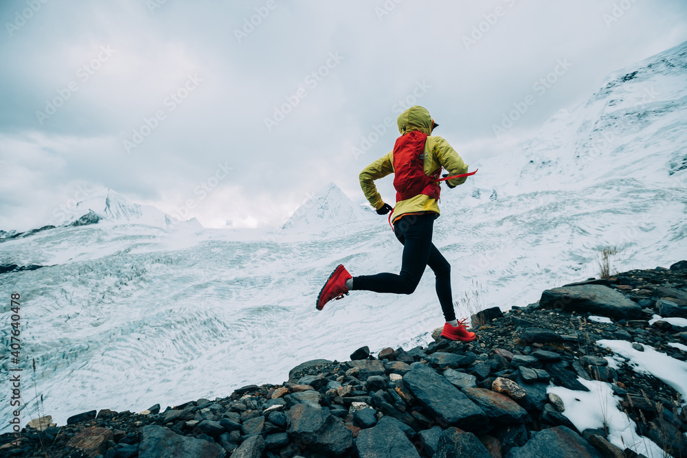 Φωτογραφία Woman trail runner cross country running up to winter snow mountain top