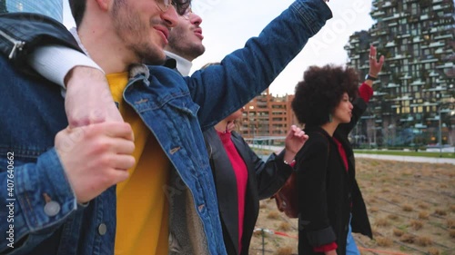 Group of friends tourist walking together hugging outdoors in the city downtown sightseeing having fun, smiling and enjoying vacation dancing and singing